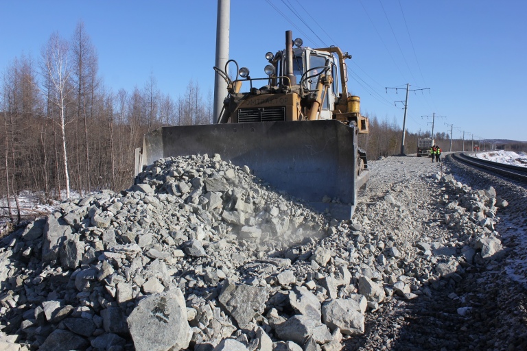 Бульдозер разравнивает скальный грунт